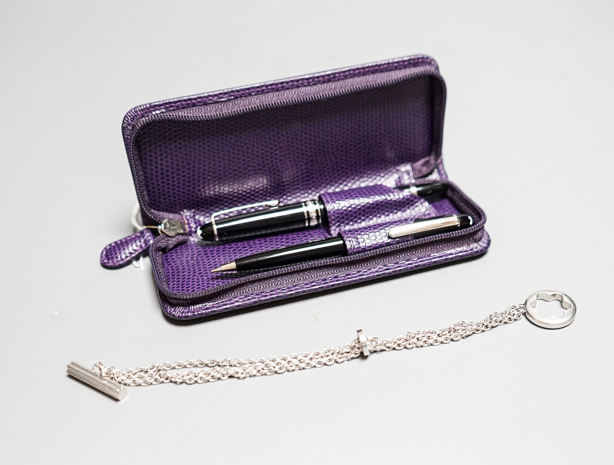 A Montblanc Meisterstuck small fountain, 11.2cm and ballpoint pen, and a chain in a purple case.